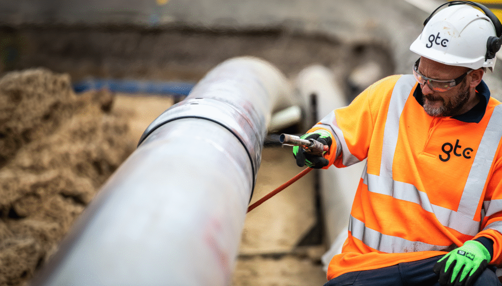 A GTC engineer installs utility pipework using a blowtorch on a new build development