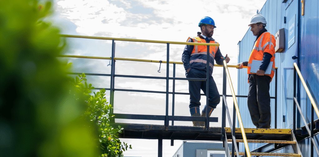 A site manager talks to an engineer in front of temporary cabins on a new build development.